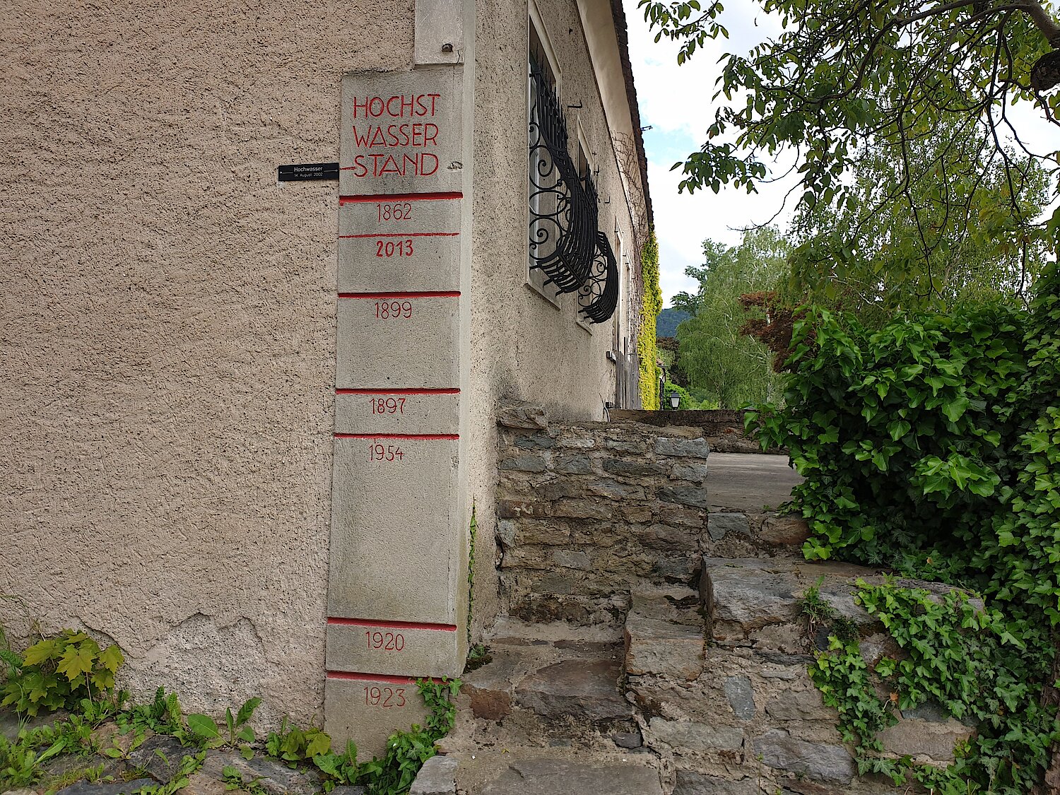 Markierung von Hochwasserständen an einer Hausecke.