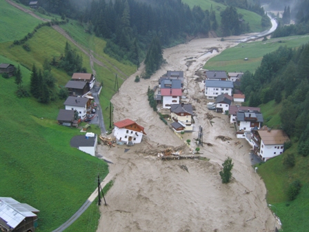 Überflutete Siedlung an einem hochwasserführenden Fluss